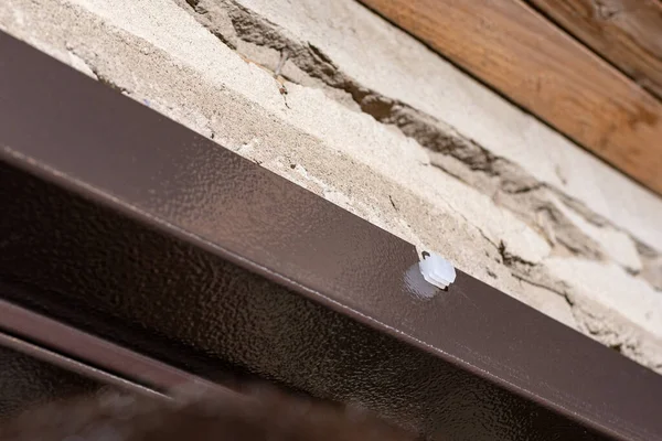 Usta ön kapıyı metal bir kutuyla kuruyor, kapı çerçevesine beyaz tıkaçlar takıyor, yakın plan 2020.