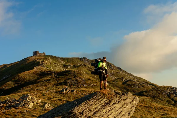 一个年轻人从皮埃文山顶下来 观察高山周围的壮丽风景 背着一个庞大的徒步旅行背包 — 图库照片