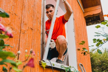 Bir pencere ve pencere çerçevesinin değiştirilmesi, kırsaldaki özel bir evin eski bir penceresinin sökülmesi, işçi eski bir ahşap pencereyi söküyor. 2020