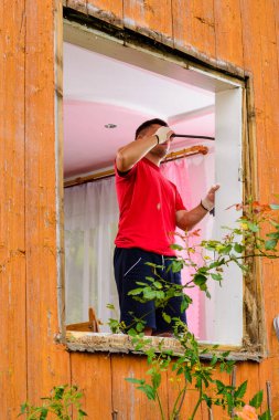 Bir adam eski ahşap bir pencereyi hurda bir metalle duvardan indirir, yakın plan eski bir pencerenin söküldüğünü gösterir. 2020