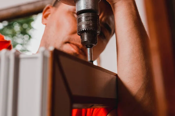 A worker installs new plastic windows in the house, drills holes in the window with a hand-held electric drill.2020