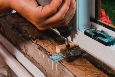 Kendi evinde bir adam plastik bir pencere takar, yeni bir pencere takar, bir işçi elektrikli matkap kullanır. 2020