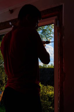 Kendi evinde bir adam plastik bir pencere takar, yeni bir pencere takar, bir işçi elektrikli matkap kullanır. 2020