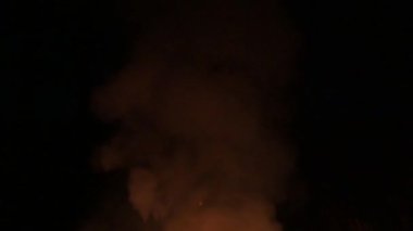 Gecenin geç saatlerinde alevler ve duman, karanlık arka planda ateşi ve dumanı yavaşlatıyor..
