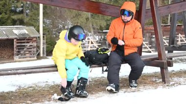 Oğlunun snowboard yapmaya hazırlanmasına yardım eden bir babanın yürek ısıtan sahnesi. Konferansta yakın bağ ve kış sporlarına hazırlık üzerinde duruluyor..