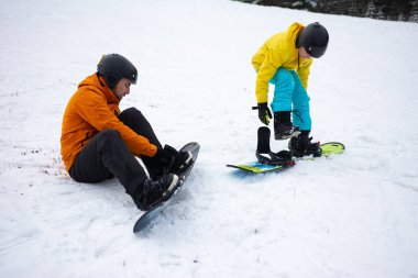 İki snowboard meraklısı kar üzerinde teçhizatlarını ayarlarken canlı bir kış günü başlıyor. Yamaçlara çarpmanın serin havasını ve heyecanını seviyorlar..
