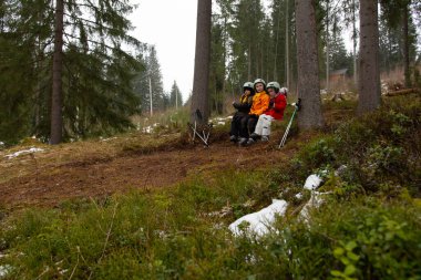 Dört arkadaş orman yolunda mola veriyor, uzun ağaçların arasında doğanın huzurunun tadını çıkarıyor ve kış havası için sıcak giyinmiş, hafif bir kar tanesi..