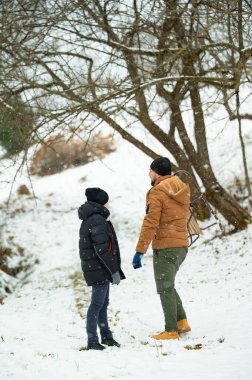 Kışın sıcacık giyinen bir adam ve çocuk, karla kaplı bir arazide dururlar. Çocuk küçük bir kızak taşıyor. Kar yavaşça düşüyor, huzurlu bir kış manzarası yaratıyor..