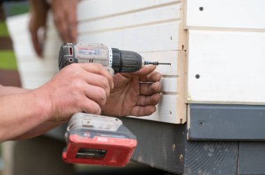 İnşaatçı pencereye vida ve tornavida, montaj ve inşaat işi kullanarak duvar ekler.