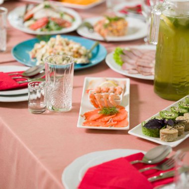 Resmi bir etkinlik için hazırlanan masada karides, somon ve çeşitli salatalar da dahil olmak üzere bir dizi lezzetli aperatifler yer alır. Ortalık rafine edilmiş ve bir kutlama havası var..
