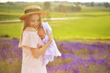 Mutlu kızı ile beyaz annesisin giyen beyaz giysiler lavanta alanında eğlenceli yaşıyorsanız. Lavanta arka plan üzerinde küçük kızı ile mutlu anne. Güzel kadın ve şirin bebek oynamak.