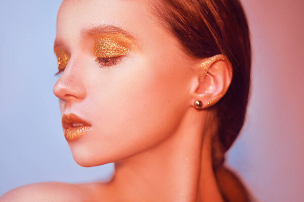 Модный портрет молодой элегантной девушки. Цветной фон, студийный снимок. Красивая брюнетка с золотыми губами и золотым ярким макияжем. Женщина со стильными волосами в неоне. Портрет лица крупным планом
.