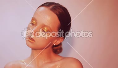 Zarif kız genç moda. Paslet arka plan, stüdyo. Altın dudaklar ve altın parlak makyaj güzel esmer kadın. Ve kadın ile şık saç olun. Poz ve parlayan, closeup saxy kız. 60fps