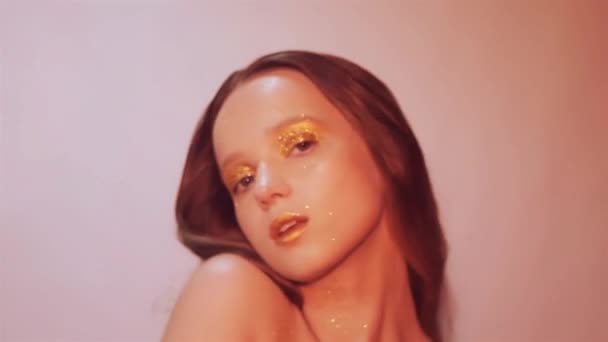 ファッション エレガントな少女 Paslet スタジオ ゴールドの唇と黄金の明るいメイクで美しいブルネットの女性 スタイリッシュな髪を持つ女性 Saxy 女の子ポーズと輝いて クローズ アップ — ストック動画