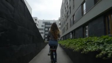 Genç kadın üzerinde bisiklete binmek ve içme kahve veya çay. Güzel yaz ruh genç kadın veya kız binicilik bisiklet şehir içinde bir kadeh. Ev Bisiklete binmek cerly saçlı kız. 60 fps