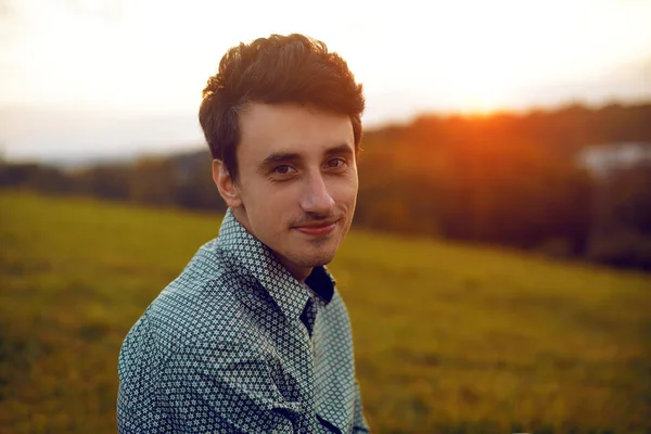 Man portrait  on sunset. Man sitting at the park on a summer day , smile boy. Student after collage, man after work. Life. Outside.