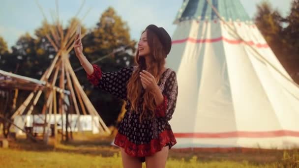年轻的妇女游客交谈在电话和微笑的背景帐篷 圆锥形帐篷印第安人的房子 旅行者聊天 年轻可爱的女孩拍照自拍视频通信 — 图库视频影像