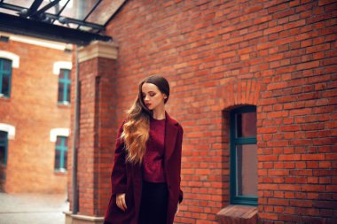 Esmer kız açık havada yaşam tarzı moda portre. Şık kırmızı palto giyiyor. Sokak şehre doğru yürümeye. Uzun kıvırcık saçları hafif. Eğlenceli ve neşeli bir kadın. Sokak moda kavramı. Yüksek moda fotoğraf