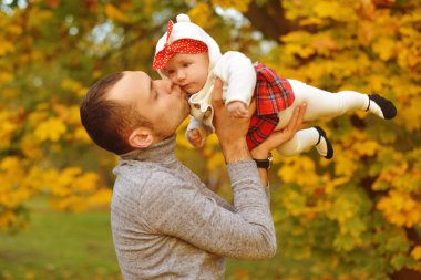 Baba ve kızı bir parkta sonbahar düşen yapraklar üzerinde güzel bir sonbahar günü zevk. Mutlu neşeli genç aile baba bebek kız açık havada eğleniyor. Uçan Bebek anne öpücüğü