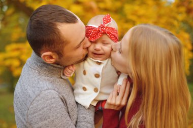 Aşk güzel bir sonbahar günü zevk sonbahar düşen yapraklar bir parkta üzerinde çift. Mutlu neşeli genç Aile Baba, anne ve bebek kız açık havada eğleniyor. Ebeveynler onların bebeği öp