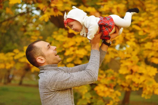 Baba ve kızı bir parkta sonbahar düşen yapraklar üzerinde güzel bir sonbahar günü zevk. Mutlu neşeli genç aile baba bebek kız açık havada eğleniyor. Uçan Bebek anne öpücüğü
