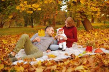 Aşık çift bir parkta sonbahar düşen yapraklar yatan, halıya yalan, güzel bir sonbahar günü zevk. Mutlu neşeli genç Aile Baba, anne ve bebek kız açık havada eğleniyor.