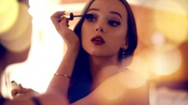 Mükemmel güzellik kız bir ayna ve does makyaj önünde ayakta. Model poz ve gülümseme, bitirme telafi. Kız uzun saçlı, kırmızı dudaklı. Kadın maskara akşam makyaj kullanır