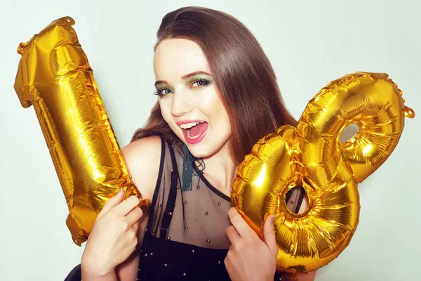 18. yaş gününde altın numaralı balonlarla doğum günü kızı. Heyecanlı 18 yaşında yeşil makyajlı ve siyah elbiseli bir kız. Mankenlik yapıp eğleniyoruz. Mutlu yıllar sana, tatlı kız..