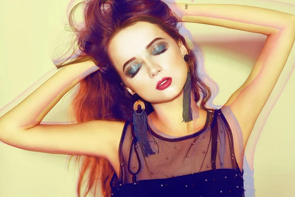 Akşam arka plan üzerinde izole yeşil makyaj ile güzel kız. Göz makyaj ve şehvetli dudakları. Esmer Püskül Bijuteri küpe ile. Yüksek moda. Siyah elbise. Neon yüksek girl dance.