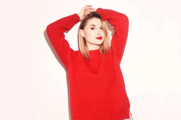 Fashion Girl in knitted red sweater . Cute blond woman Warming Up Concept. Pretty girl with empty copy space near. Beautiful teen girl with red lips.