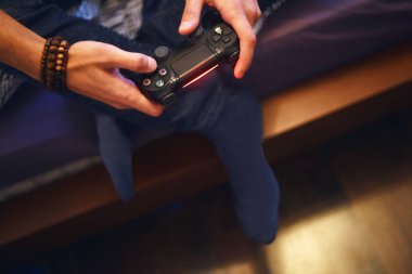 Video oyunu bağımlısı genç adam konsoluyla oynarken. Siyah bir oyun controlle tutan genç adam