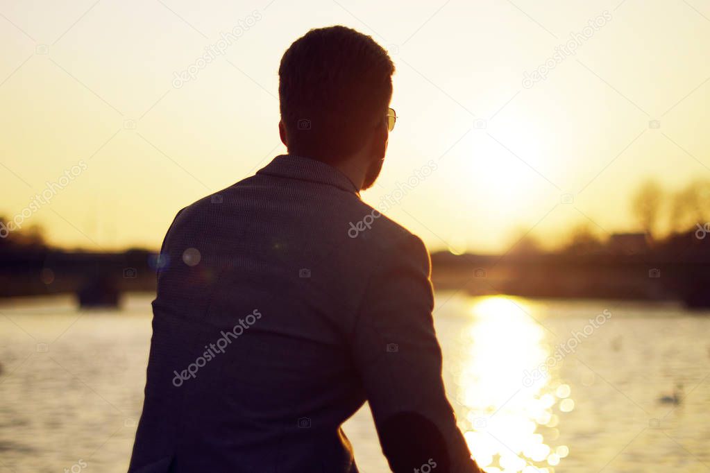 Silhouette of a man . sunset lake and river nature background beautiful sky. Businessman looks into the distance and ponders, thinks, dreams.