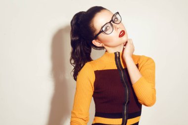 Şık gözlük Güzellik esmer modeli kız moda. Mükemmel makyaj, trendy turuncu ve kırmızı elbise ve moda giyim seksi kadınla. Güzellik trendleri. Kırmızı dudaklar ve gözlük ile kız. Öğrenci.