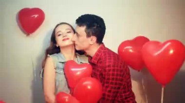 Erkek, tatlı kızına hediye yapar. Sevgililer Günü 'nde. Sevgililer Günü. Adam kalp kutusunda sevgilisine şeker veriyor. Arka plan kırmızı balonlar kalpler. Erkek kızı öper..