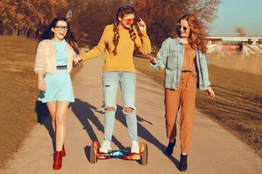 Hoverboard üç güzel kız. Kız ilişkileri, yürüyüş, aktif, yeni modern teknolojiler. Kızlar kız hoverboard binmek için öğretmek. Güneşli bir gün, kızlar eğleniyor, gülümse, açık.