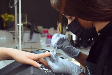 Efendi manikür yapıyor. Güzellik salonunda dinlenme günü. Manikürcü kadın eline manikür yapıyor. Tırnak boyası, oje boyası, tırnak cilası. Usta tırnak törpüsü keser