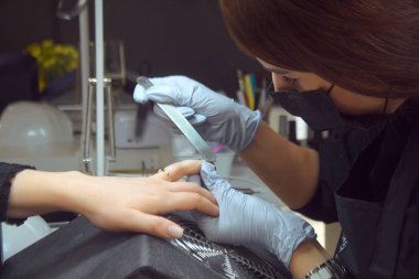 Efendi manikür yapıyor. Güzellik salonunda dinlenme günü. Manikürcü kadın eline manikür yapıyor. Tırnak boyası, oje boyası, tırnak cilası. Usta tırnak törpüsü keser