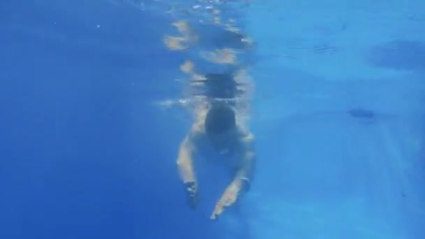 那个穿泳衣的男人在水下游泳 男孩游到相机前 水下射击一个留着长发的男人跳水 — 图库视频影像