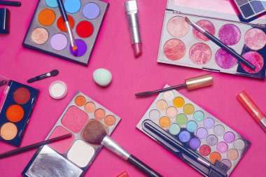 Krem, ruj, toz, maskara ve fırçalar. Makyaj için gölgeler, süngerler, parlaklık. Parlak bir arka planda kadın kozmetik. Satış, indirimli kozmetik. Pembe arka planda üstgörünüm. 