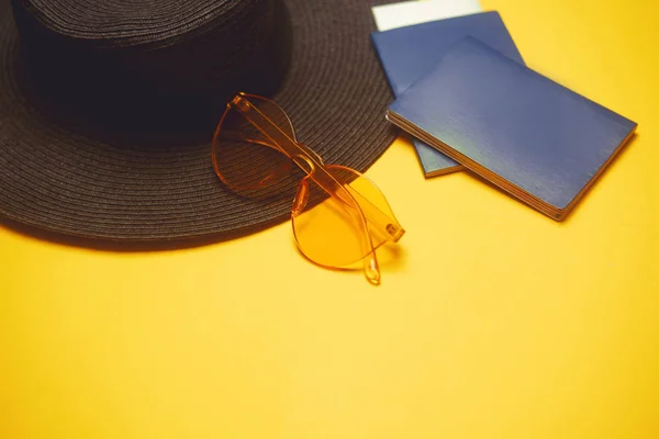 Travels. Hat, 2 passports, plane tickets and glasses on an orange background. Empty place for text. Travel discounts. Holidays, Summer.