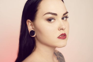 Kulaklarında bir tünel olan bir esmer portresi ve delinmiş 