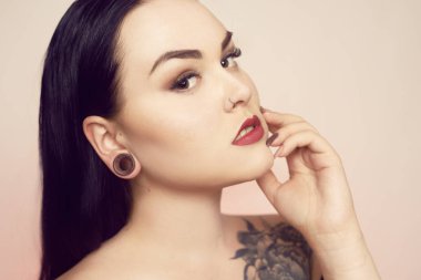 Kulaklarında bir tünel olan bir esmer portresi ve delinmiş 