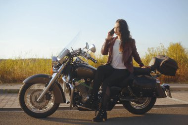 Gün batımında motosikletli bir kız. Bisiklete yakın alanda kız 