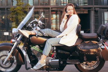 Güzel sarışın ofis yakınında bir motosiklet üzerinde oturur. Kız 