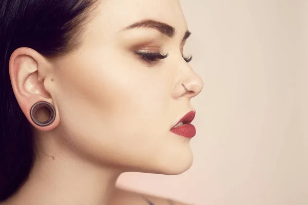 Retrato de una morena con un túnel en las orejas y un piercing —  Fotos de Stock