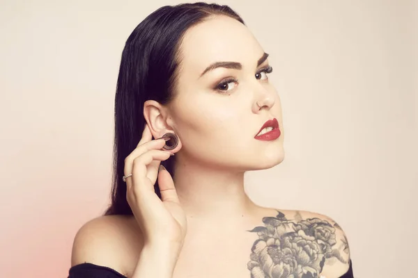 Portrait of a brunette with a tunnel in her ears, and a pierced — Stock Photo, Image