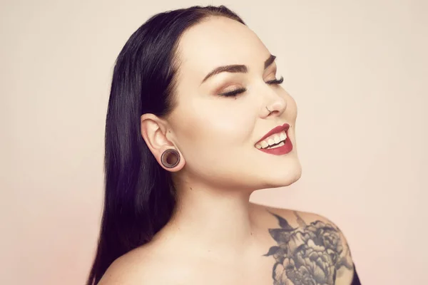 Portrait of a brunette with a tunnel in her ears, and a pierced — Stock Photo, Image