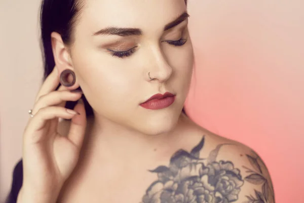 Portrait of a brunette with a tunnel in her ears, and a pierced — Stock Photo, Image