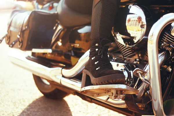 Biker girl riding on a motorcycle. Bottom view of the legs in le