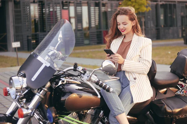 Linda loira senta-se em uma motocicleta perto do escritório. A menina — Fotografia de Stock